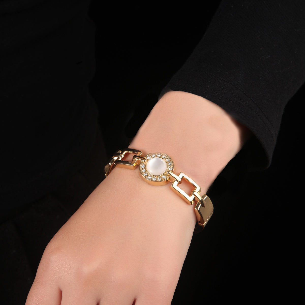 Gold chain-link halo bangle with opal center, worn